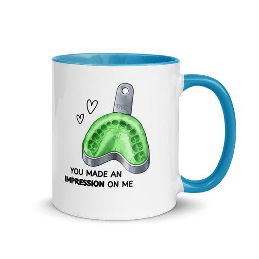 Weiße Keramiktasse mit farbigem Henkel und Innenseite sowie Abdrucklöffel-Motiv mit grünem Abformmaterial und Schriftzug „You made an impression on me“ – humorvolle Dental-Tasse für Zahnmedizin und Kieferorthopädie